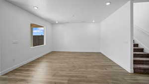 Unfurnished room with stairs, light wood-type flooring, recessed lighting, and a textured ceiling