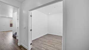 Corridor with light wood finished floors, stairs, and recessed lighting