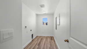 Laundry area with a textured ceiling, light wood finished floors, hookup for an electric dryer, and electric panel