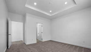 Unfurnished bedroom with carpet floors, a tray ceiling, and recessed lighting