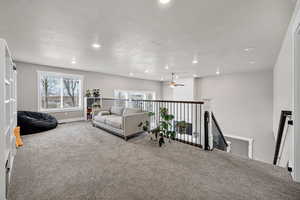 Living area with carpet flooring, an upstairs landing, ceiling fan, and recessed lighting