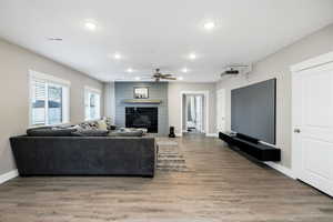 Living room featuring a large fireplace, light wood-type flooring, recessed lighting, and a ceiling fan