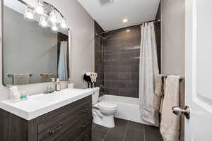Bathroom featuring vanity, shower / tub combo, and dark tile patterned flooring