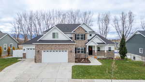 View of front facade with a front lawn, brick siding, driveway, and roof with shingles