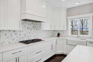 Kitchen with white cabinetry, decorative backsplash, and light stone countertops