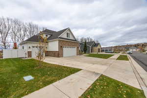 View of front of property with brick siding, concrete driveway, an attached garage, and a gate