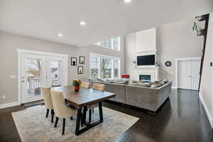 Dining space with a glass covered fireplace, dark wood-style flooring, a towering ceiling, and recessed lighting