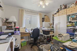 Office area with dark wood-style flooring and ceiling fan