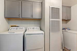 Laundry area featuring a heating unit, cabinet space, independent washer and dryer, and a decorative wall