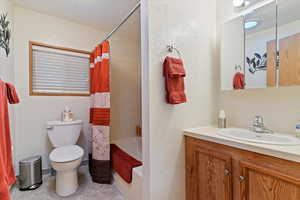 Full bathroom with shower / bath combo, vanity, and a textured wall
