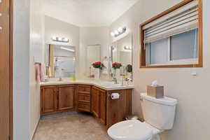 Full bath with a textured wall, double vanity, and a shower with door