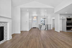Unfurnished living room with a tile fireplace, a chandelier, wood finished floors, and recessed lighting