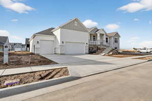 Ranch-style home with a porch, concrete driveway, board and batten siding, stone siding, and a garage