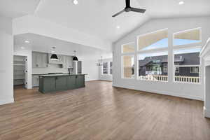 Unfurnished living room featuring dark wood-style flooring, ceiling fan, high vaulted ceiling, recessed lighting, and a chandelier