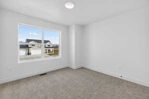 Carpeted spare room featuring baseboards