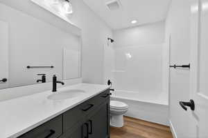 Bathroom with vanity, shower / tub combination, and dark wood finished floors