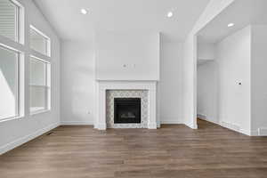Unfurnished living room featuring recessed lighting, wood finished floors, and a tiled fireplace