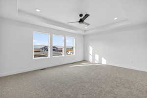 Unfurnished room with a tray ceiling, ceiling fan, light colored carpet, and recessed lighting