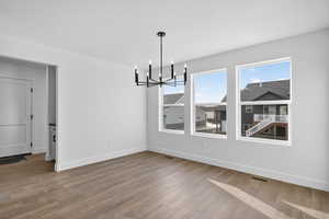 Unfurnished dining area with a chandelier and light wood-style flooring