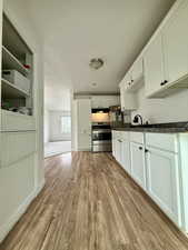 Kitchen with light wood-type flooring, white cabinetry, and stainless steel electric range oven