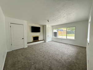 Unfurnished master bedroom featuring a brick fireplace, double closets, a textured ceiling, and carpet floors