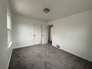 Unfurnished bedroom with dark carpet and baseboards