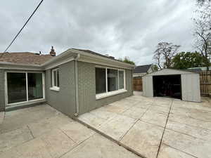View of backof property featuring a storage shed, a patio area, a fenced backyard, brick siding, and a chimney,vsolar panels
