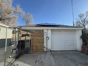 Garage with driveway, a gate, and solar panels