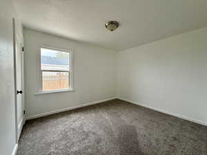 Unfurnished bedroom featuring dark carpet and baseboards