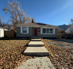 View of front facade featuring solar panels, a chimney, and brick siding