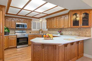 Kitchen with brown cabinets, light countertops, stainless steel appliances, and a peninsula