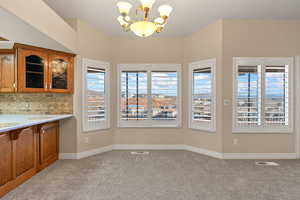 Unfurnished dining area with a chandelier and light carpet