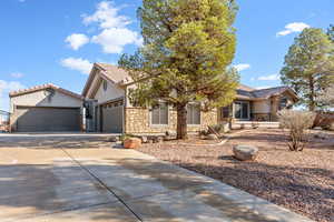 View of front of home featuring stone siding, driveway, stucco siding, a tiled roof, and an attached garage