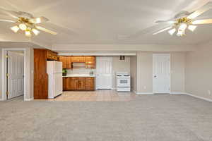 Kitchen featuring a ceiling fan, light colored carpet, light countertops, white appliances, and a textured ceiling