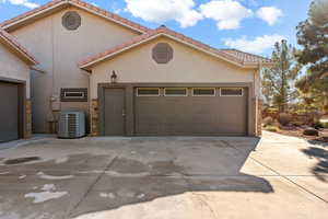 View of front of house featuring a tile roof, concrete driveway, stucco siding, stone siding, and a garage
