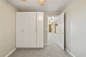 Unfurnished bedroom featuring light carpet, ceiling fan, freestanding refrigerator, and a textured ceiling