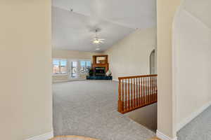 Hall featuring arched walkways, light colored carpet, and vaulted ceiling
