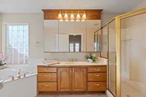 Full bath featuring vanity, a garden tub, and a stall shower