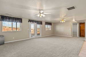 Unfurnished room featuring a textured ceiling, light colored carpet, and ceiling fan