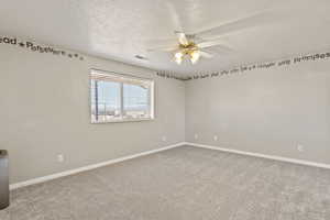 Unfurnished room featuring light carpet, a textured ceiling, and ceiling fan