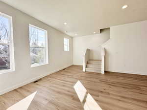 Unfurnished living room featuring recessed lighting, stairs, light wood-style flooring, and a textured ceiling