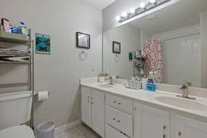 Bathroom with double vanity, a shower with curtain, and light marble finish flooring