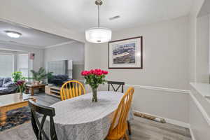Dining space with light wood-style floors and a textured ceiling