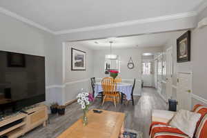 Living room featuring wood finished floors, ornamental molding, and a textured ceiling