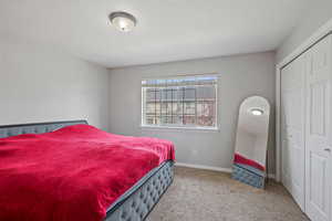 Bedroom with a textured ceiling, light colored carpet, and a closet
