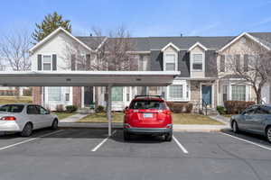 View of front of house with covered and uncovered parking, brick siding, a shingled roof, and entry steps
