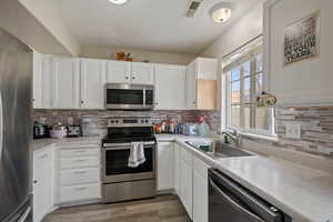 Kitchen featuring stainless steel appliances, light countertops, white cabinetry, a textured ceiling, and dark wood-style flooring