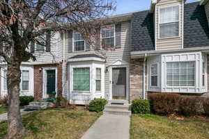 View of front of home with brick siding, roof with shingles, and a front lawn