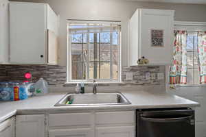 Kitchen with white cabinetry, light countertops, and dishwashing machine