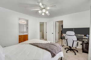 Bedroom featuring light carpet, a ceiling fan, a walk in closet, and an office area